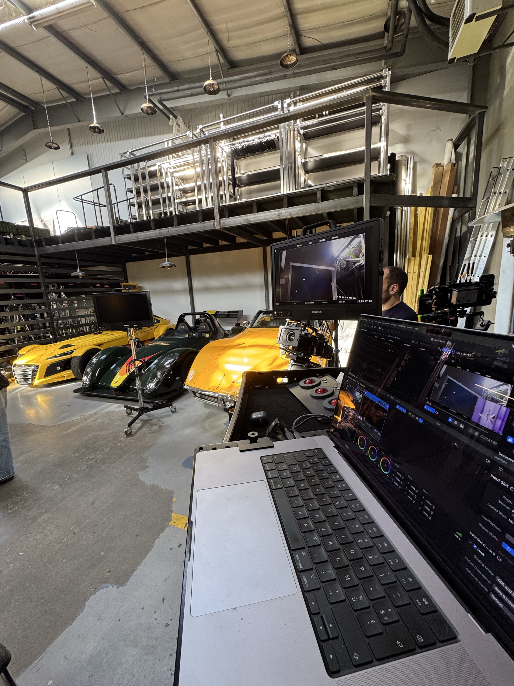 A D.I.T cart with monitor and grading laptop in an industrial garage of yellow sports and race cars